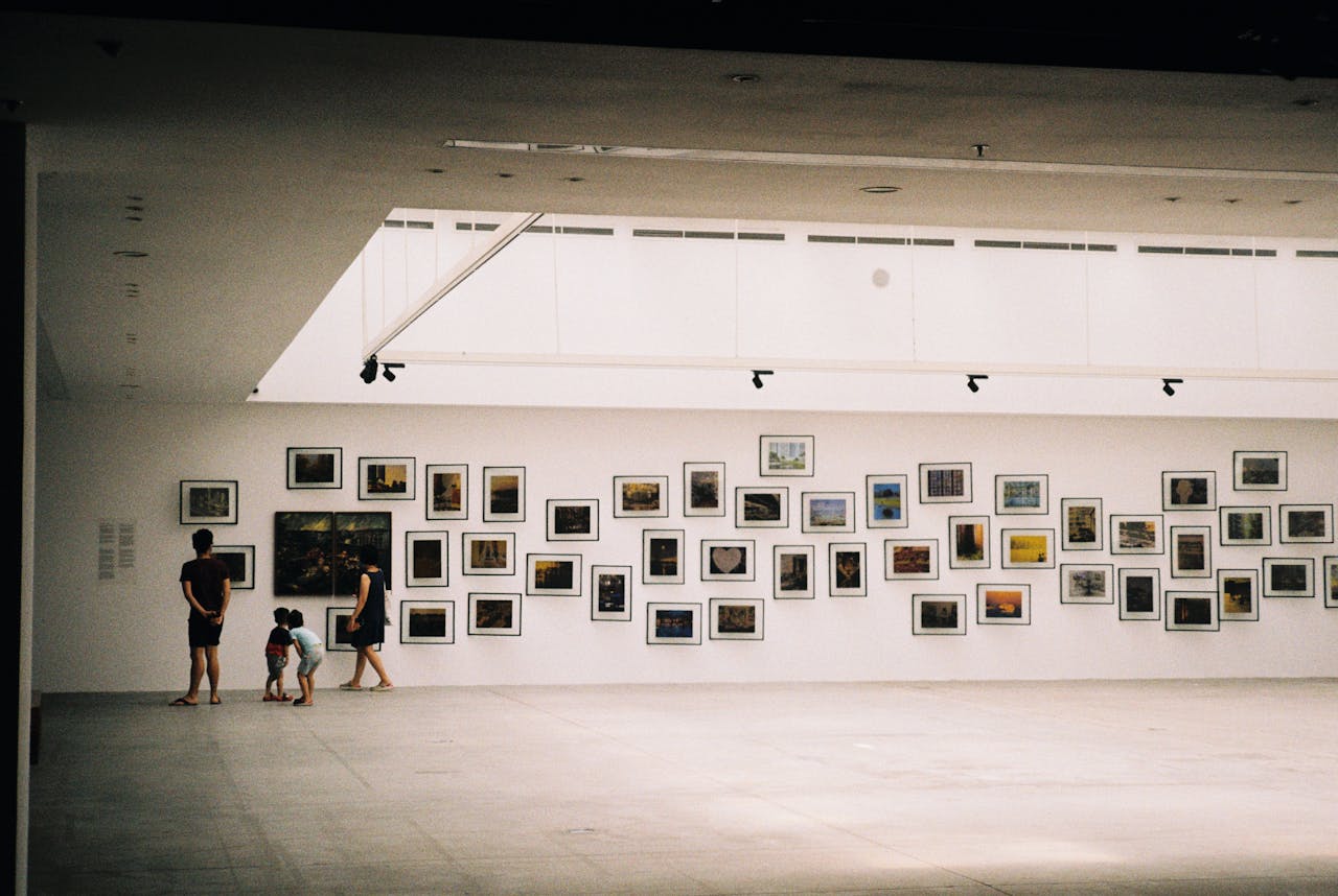 A family exploring an art exhibition in a modern gallery with framed artworks displayed on the wall.