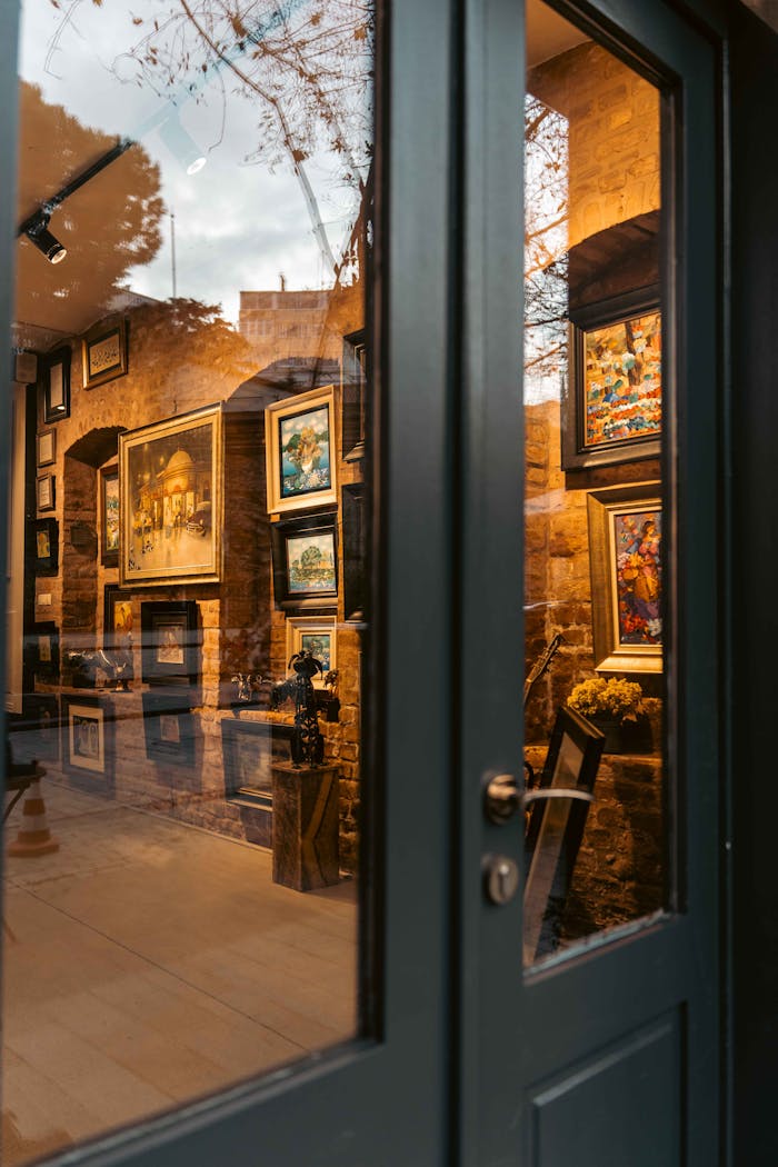 A cozy art gallery interior with framed paintings viewed through glass door.