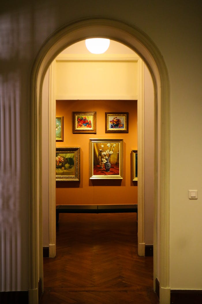A well-lit corridor leading to an art gallery display with elegant framed paintings.